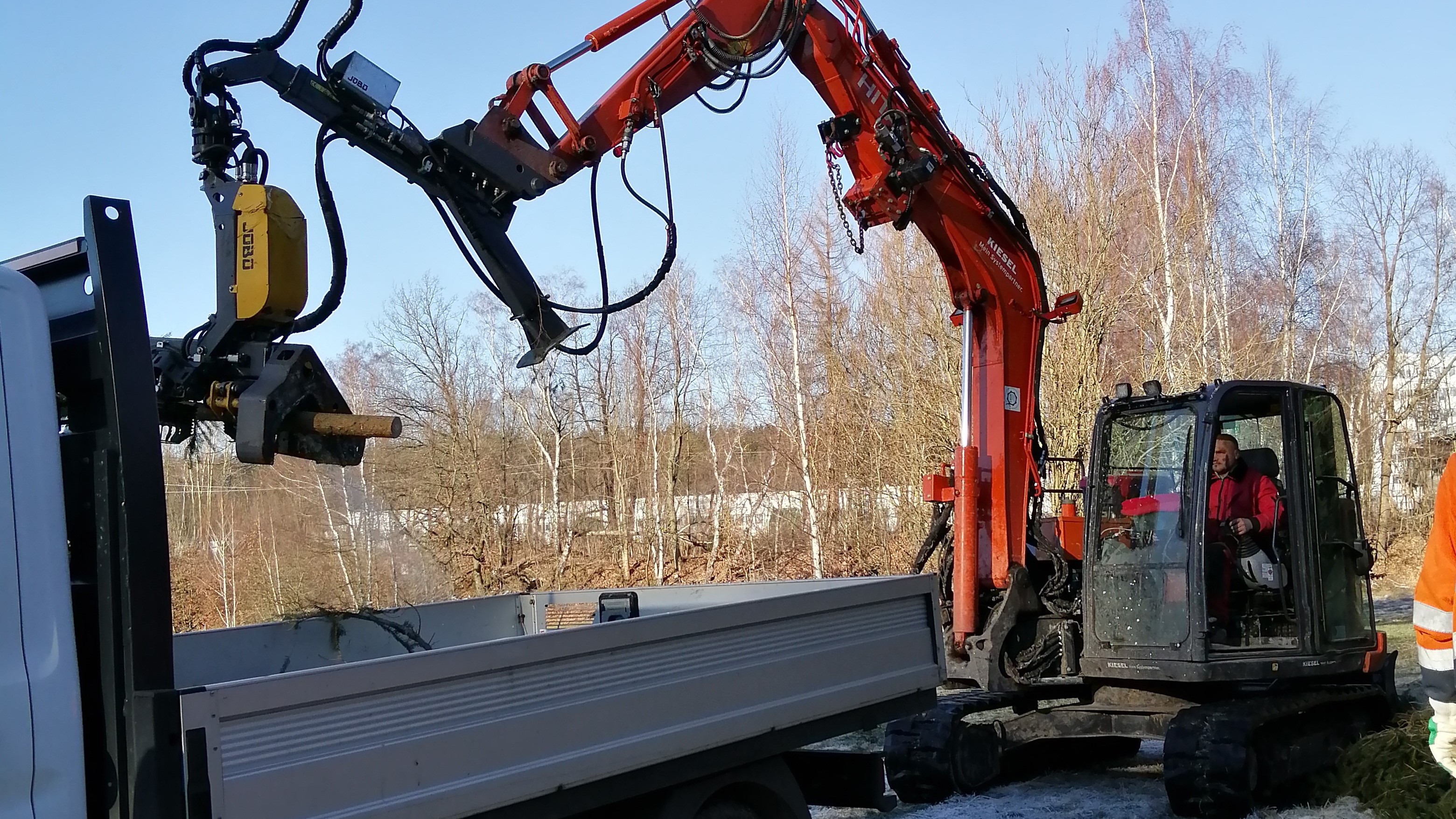 Hitachi ZX 85 mit Harvester bei der Direktverladung von auf Wunsch abgelängtem Holz